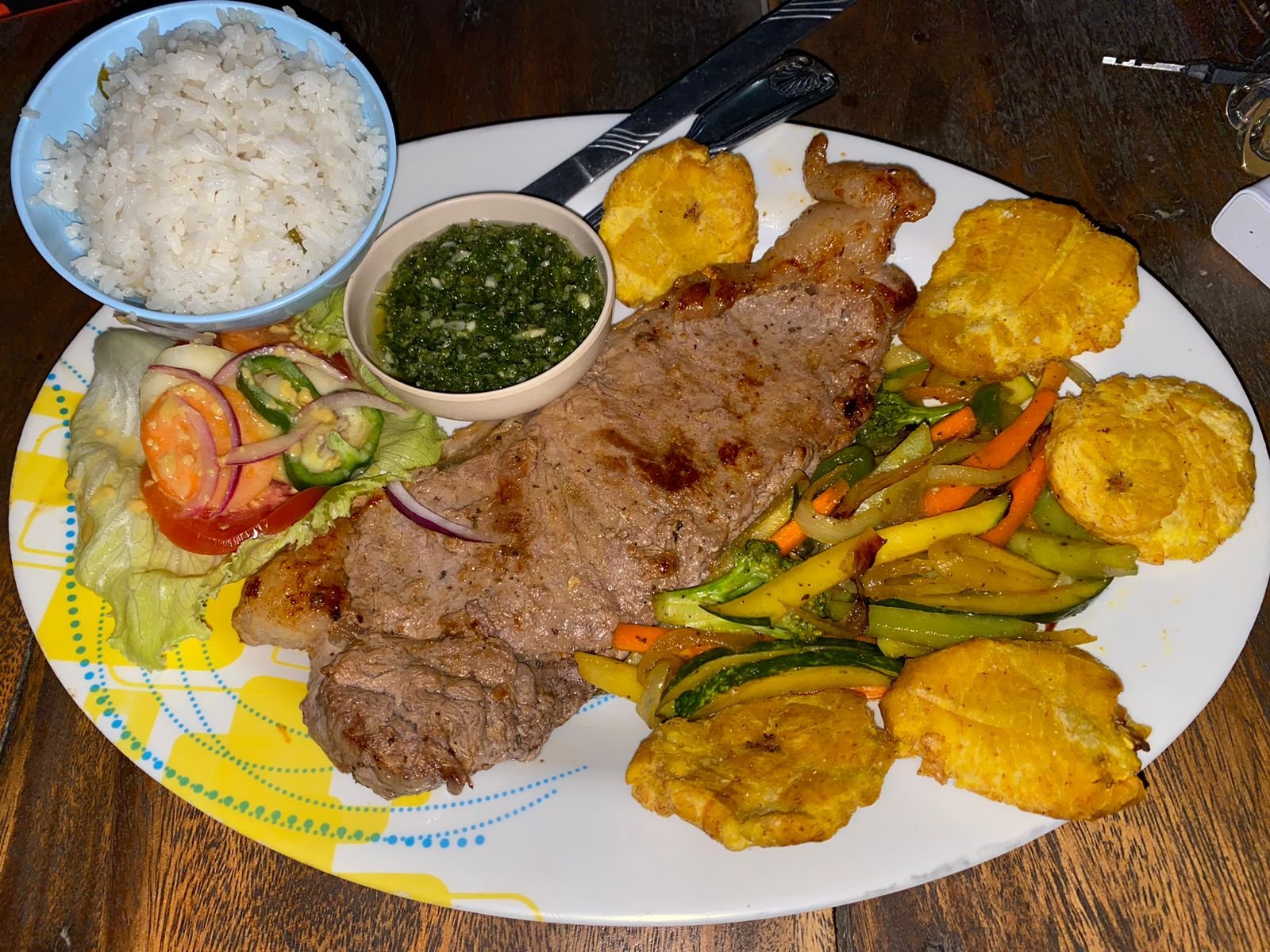 Plato de carne acompañado de arroz, vegetales y tostones